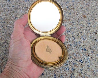 Estuche compacto para damas en tono dorado de KIGU que puede contener polvos sueltos para el rostro en buen estado vintage.