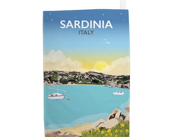 Puede incluir: Una toalla de cocina azul y blanca con una ilustración colorida de una bahía en Cerdeña, Italia. El texto "Cerdeña Italia" está impreso en la toalla.