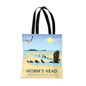 Könnte beinhalten: Eine Tragetasche mit einer farbenfrohen Illustration einer Strandszene mit einem Schiffswrack, einer Möwe, die überfliegt, und einer strahlend gelben Sonne. Der Text "WORM'S HEAD Rhossili Gower Peninsula, Swansea" ist auf der Tasche aufgedruckt.