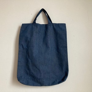 Op de afbeelding: Een donkerblauwe canvas tas met twee handvatten.