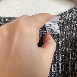 May include: A black and white knit sweater with a white tag that reads "$21% Acrylic, 38% Silk, 10% Mohair. See reverse for care. Voir au verso pour entretien."