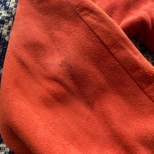 May include: Close-up of a rust-colored fabric with a textured surface.