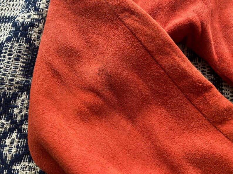 May include: Close-up of a rust-colored fabric with a textured surface.