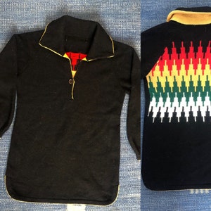 Könnte beinhalten: Schwarzer Pullover mit gelbem Saum und einem kontrastierenden roten, gelben und grünen geometrischen Muster auf der Rückseite.
