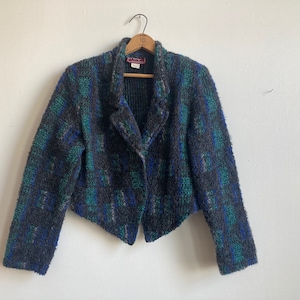May include: A cropped black, blue, and green patterned blazer with a single button closure.