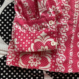 May include: Pink and white patterned fabric with white buttons. The fabric has a floral design.
