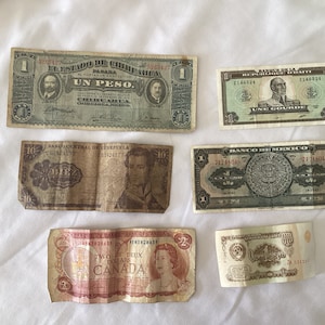 May include: Collection of vintage banknotes from various countries, including a one-peso bill from Mexico, a ten-bolivar bill from Venezuela, a two-dollar bill from Canada, and other currency notes. The bills are in various states of wear.