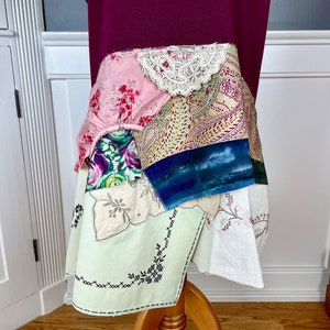 May include: A patchwork skirt made from various fabrics, including floral prints, lace, and paisley patterns. The skirt is layered and has a unique, bohemian style.