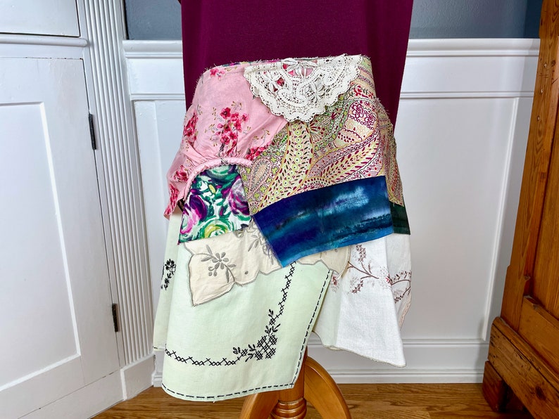 May include: A patchwork skirt made from various fabrics, including floral prints, lace, and paisley patterns. The skirt is layered and has a unique, bohemian style.