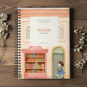 May include: A spiral-bound notebook titled Woodland Writers Cursive Copywork: Matilda by Roald Dahl by Whimsy Printables. The cover features a watercolor illustration of a bookstore with a bookshelf and a girl holding books near a green door.