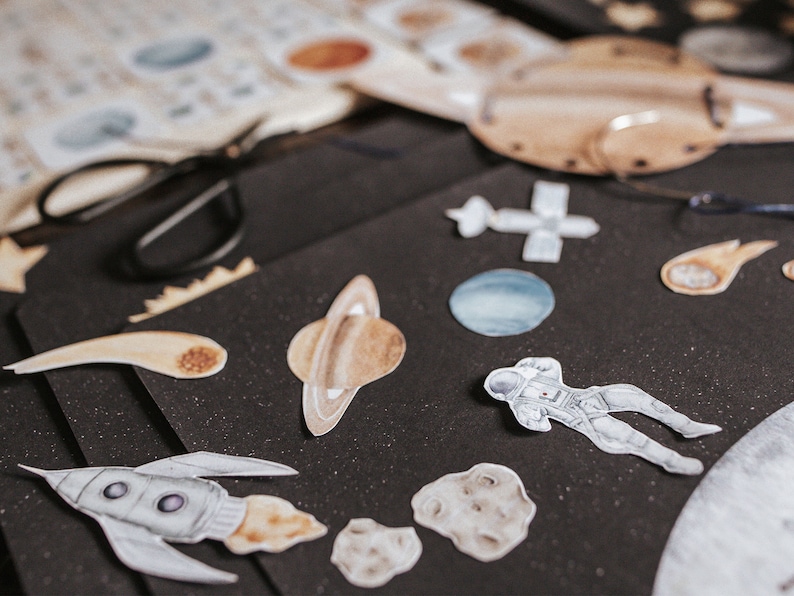 May include: A collection of space-themed stickers on a black background. The stickers include planets, a rocket ship, an astronaut, and a comet.