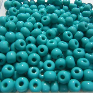 May include: A large quantity of turquoise blue glass beads. The beads are round and have a smooth, glossy finish.