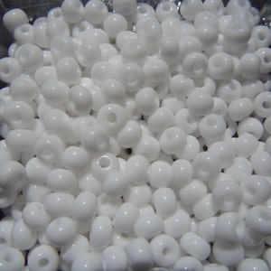 May include: A large quantity of white round seed beads. The beads are opaque and have a smooth, glossy finish.