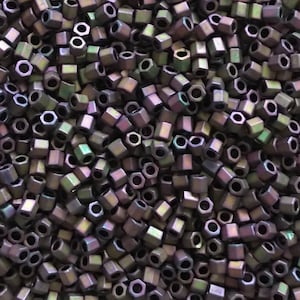 May include: A close-up view of a large quantity of dark purple iridescent hexagonal beads. The beads have a metallic sheen and are arranged in a random pattern.
