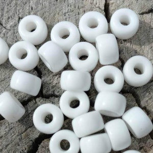 May include: A collection of white plastic beads with a hole in the center. The beads are round and have a smooth surface.