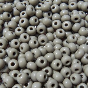 May include: A large quantity of small, round, gray beads. The beads are made of plastic and have a smooth, glossy finish.