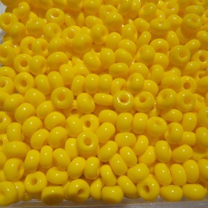 May include: A close-up image of a large quantity of bright yellow seed beads. The beads are small and round, with a hole in the center. They are perfect for crafting and jewelry making.