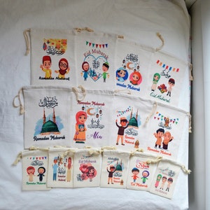 May include: A collection of 12 colorful drawstring bags with various designs featuring cartoon characters, Islamic calligraphy, and the phrase "Ramadan Mubarak" or "Eid Mubarak".