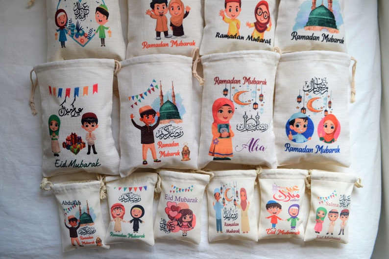 May include: A collection of 12 small drawstring bags with various designs featuring cartoon children, Islamic calligraphy, and the phrase "Ramadan Mubarak". Some bags also include the phrase "Eid Mubarak".