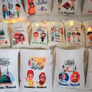 May include: A collection of 12 small, white drawstring bags with various colorful designs featuring cartoon children, Islamic calligraphy, and the phrases "Ramadan Mubarak" and "Eid Mubarak".