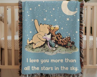 May include: A blue woven throw blanket with a scene of Winnie the Pooh, Piglet, and Tigger looking up at the stars. The blanket has a white crescent moon and the text "I love you more than all the stars in the sky."