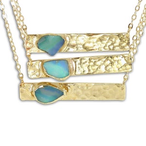 May include: A gold necklace with three layered bars, each featuring a different sized opal gemstone. The opals are a light blue-green color.
