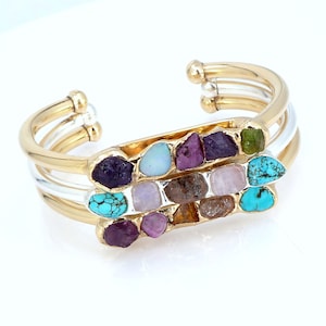May include: Gold and silver bangle bracelet with a row of colorful gemstones, including turquoise, amethyst, opal, ruby, and rose quartz.