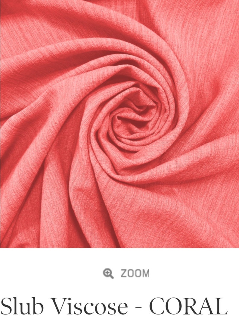 May include: Close-up of a coral-colored slub viscose fabric, showing its soft, textured surface and the way it drapes.
