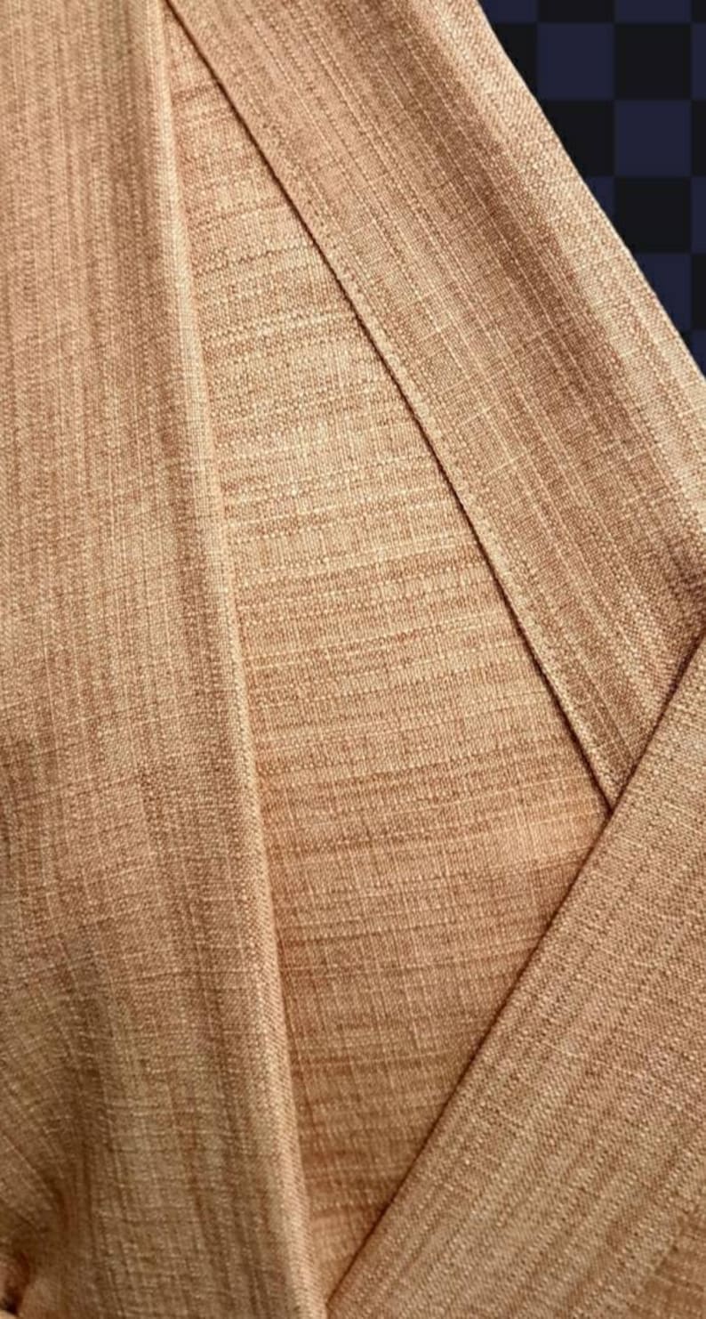 May include: Close-up of a brown fabric with a textured weave. The fabric is folded over itself, creating a diagonal line.