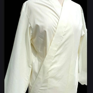 May include: A white long-sleeved shirt with a mandarin collar and a wrap-style closure. The shirt is made of a lightweight fabric and has a relaxed fit.