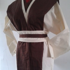 May include: A brown and white robe with a long sleeve and a belt. The robe has a V-neck and a collar.