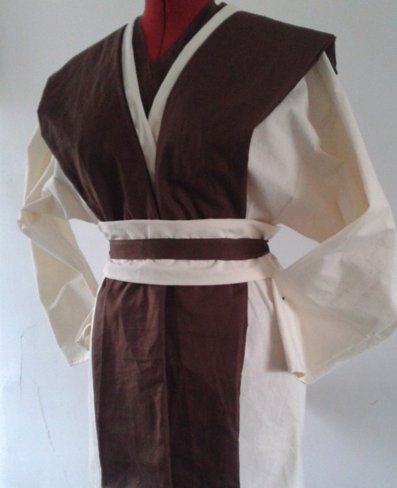 May include: A brown and white robe with a long sleeve and a belt. The robe has a V-neck and a collar.