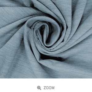 May include: Close-up of a soft, blue, textured fabric with a slub weave. The fabric is folded and twisted, creating a swirling pattern. The fabric is called "Slub Viscose - Pewter".