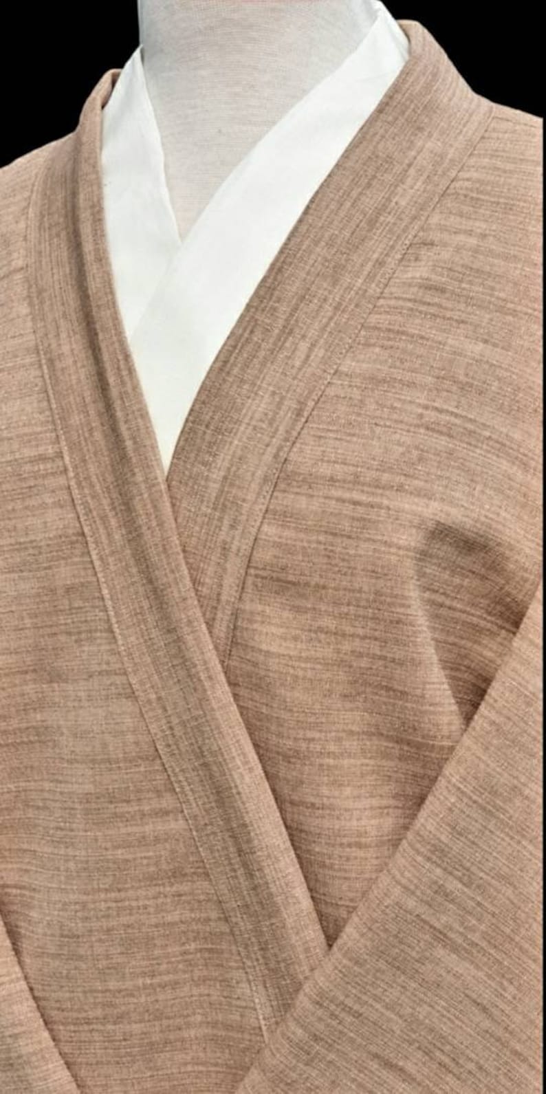 May include: A brown, textured, long-sleeved robe with a white collar. The robe is open in the front, revealing the white collar underneath.