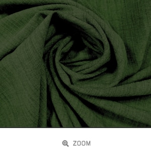 May include: A close-up of a soft, green fabric with a textured, slubby weave. The fabric is folded and draped, showcasing its drape and texture.