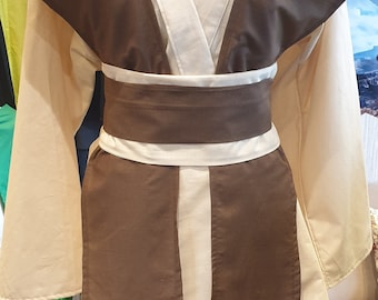 Könnte beinhalten: Eine braune und weiße Robe mit einem weißen Gürtel. Die Robe hat einen V-Ausschnitt und lange Ärmel. Der Gürtel ist in der Taille gebunden.