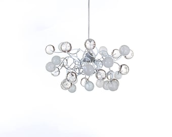 May include: A white metal chandelier with multiple clear and frosted glass globes. The chandelier has a modern design with a cluster of globes hanging from a central point.