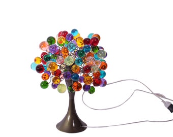 May include: A colorful glass ball tree lamp with a bronze base and a white cord. The lamp is lit and the glass balls are illuminated.