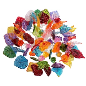 May include: A colorful glass leaf mobile with leaves in shades of red, orange, yellow, green, blue, purple, and pink. The leaves are suspended from a central point and are arranged in a circular pattern.