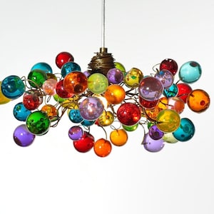 May include: A multi-colored pendant light fixture featuring numerous translucent glass spheres in shades of red, blue, green, yellow, orange, and purple, attached to a central dark metal frame with a coiled wire top and a single suspension cord.