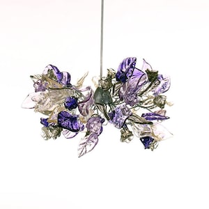 May include: A purple and clear glass chandelier with a floral design. The chandelier is hanging from the ceiling and is lit up.