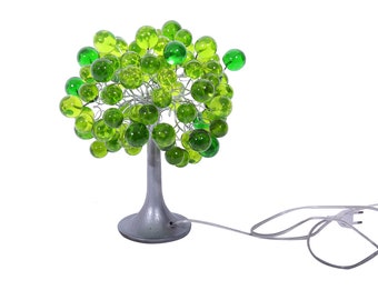 May include: A green glass ball tree lamp with a silver base and a white cord. The lamp is lit and the glass balls are glowing.
