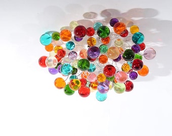 May include: A decorative light fixture featuring numerous colorful glass orbs in shades of red, orange, green, purple, and clear. The orbs are connected by thin, silver-colored wires, creating a clustered, artistic design.