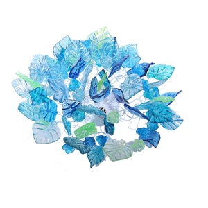 Könnte beinhalten: Ein blauer und grüner Glasblattlüster mit einem weißen Drahtrahmen. Die Blätter sind aus Glas und in verschiedenen Blautönen und Grüntönen gehalten.