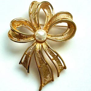 Broche vintage Napier con lazo dorado, centro de perla artificial y diseño calado