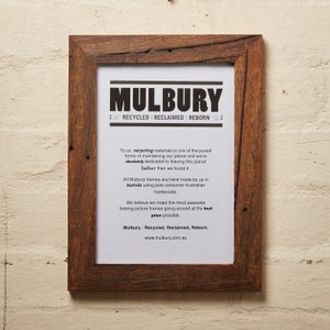 May include: A wooden picture frame with a rustic brown finish. The frame has a white mat and a printed message that reads "Mulbury - Recycled, Reclaimed, Reborn." The text also includes the website address "www.mulbury.com.au".