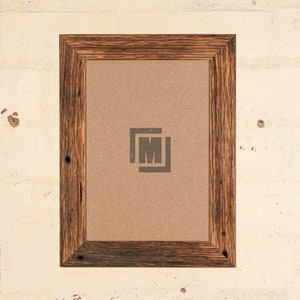 May include: A rustic wooden picture frame with a brown cardboard backing. The frame has a dark brown stain and a visible wood grain. The frame is empty and ready for a picture.