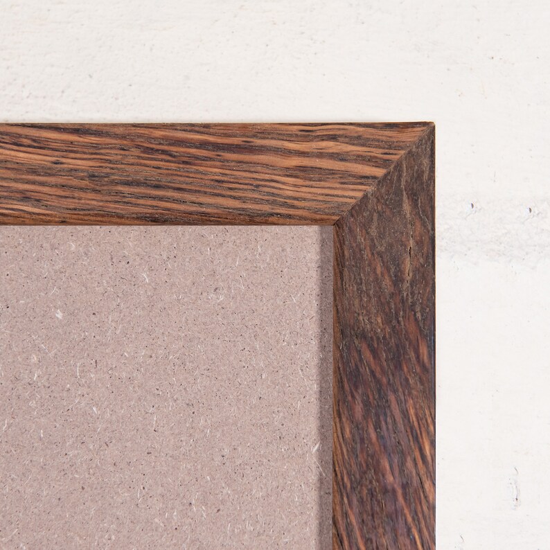 May include: A brown wooden picture frame with a light brown mat. The frame is made of wood with a natural grain pattern.