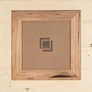 May include: A square wooden picture frame with a natural wood finish. The frame has a rustic look with knots and grain patterns. The frame is empty and ready to display a photo or artwork.