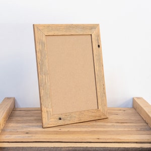 May include: A rustic wooden picture frame with a natural wood finish. The frame is made of reclaimed wood and has a distressed look. The frame is empty and ready to be filled with a photo or artwork.